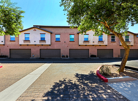 A tree is in front of a building with a red planter.