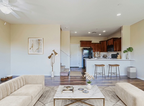 A living room with a white couch, a coffee table, and a kitchen area in the background.