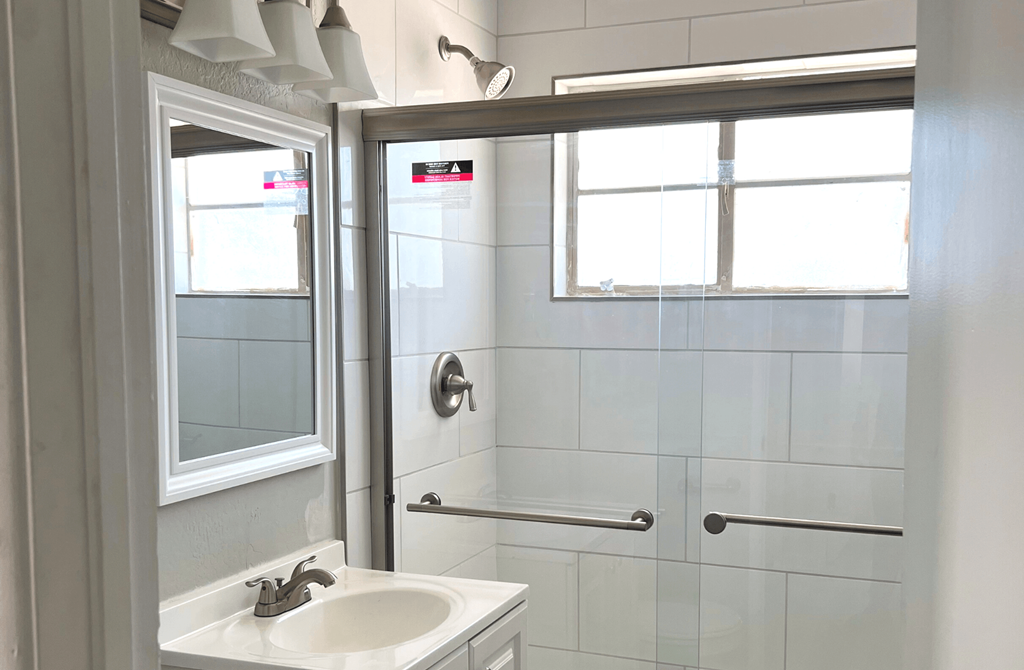 A white sink in a bathroom with a glass shower door.