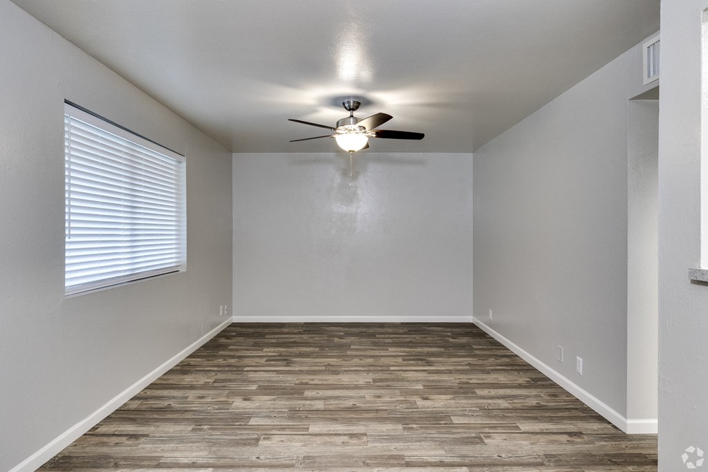 an empty bedroom with a ceiling fan and a window