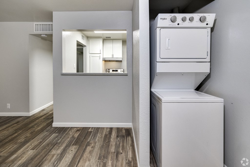 an empty apartment with a washer and dryer and a kitchen