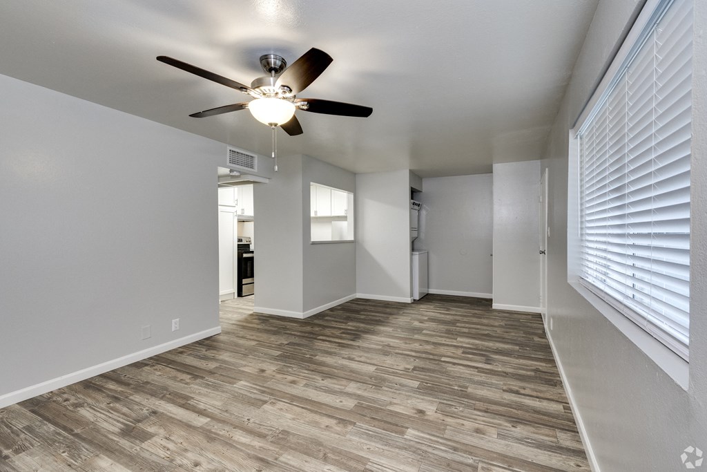 an empty living room with a ceiling fan and a window