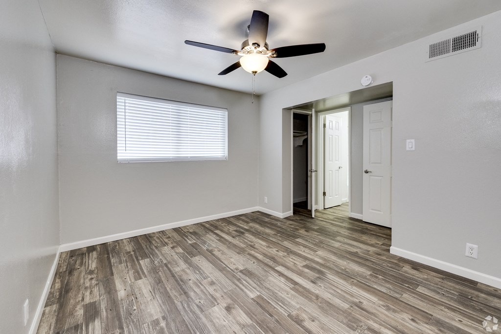 an empty living room with a ceiling fan and a door to a hallway
