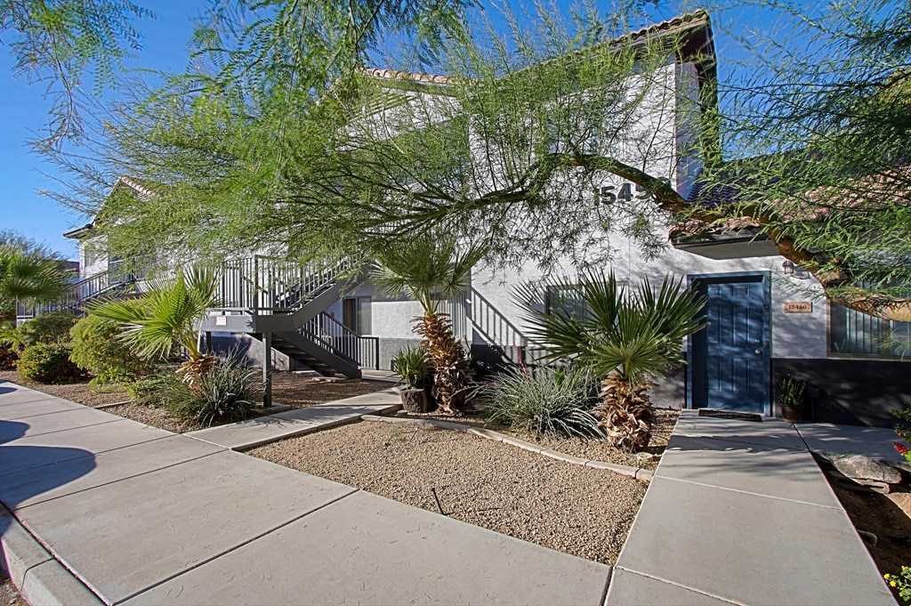 a sidewalk in front of a house with a blue door