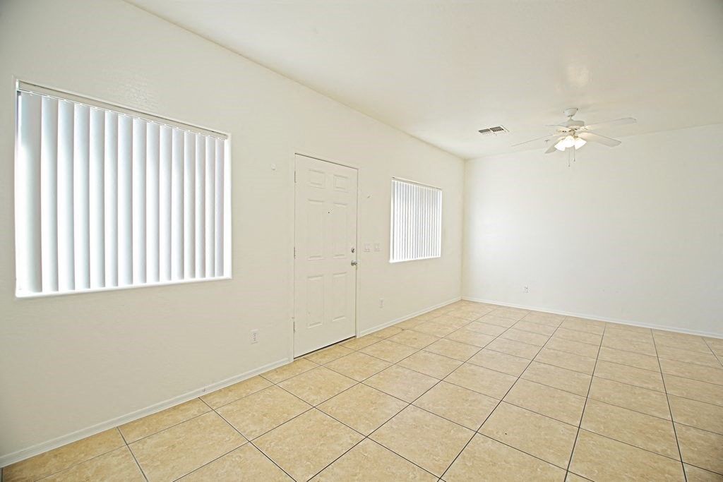 an empty living room with tile flooring and a door