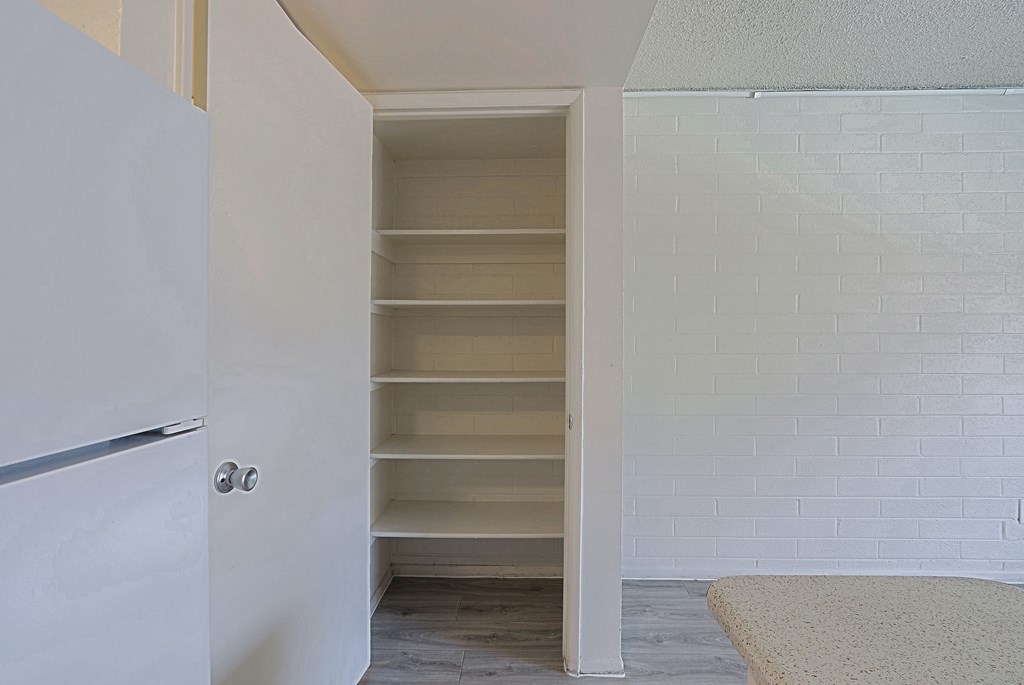 A white hallway with a white door and a white brick wall.