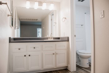 a bathroom with white cabinets and a black countertop - Photo Gallery 16
