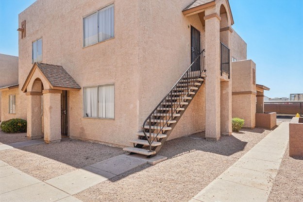 A beige stucco house with a black metal staircase.