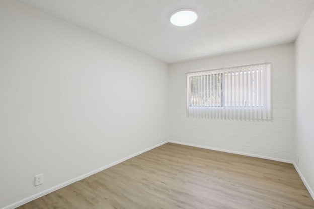 A room with a window and wooden flooring.