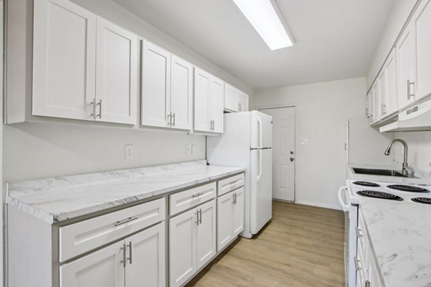 A kitchen with white cabinets and appliances.