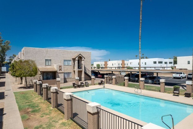 A pool surrounded by a black fence in front of a building.