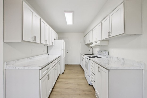 A white kitchen with wooden floors and white appliances.