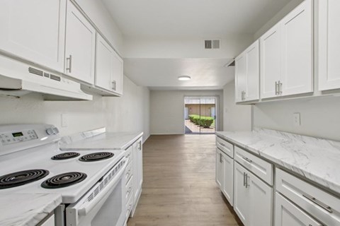 A white kitchen with a stove top oven and cabinets.