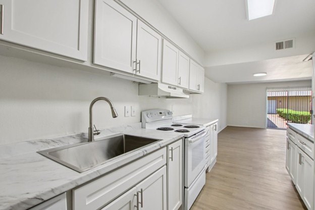 A kitchen with white cabinets and a marble countertop.