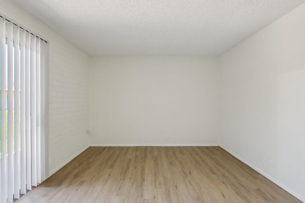 A room with wooden flooring and white walls.