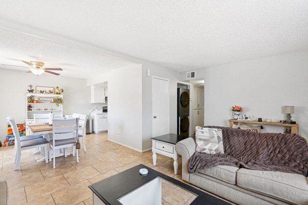 A living room with a grey couch and a dining table.