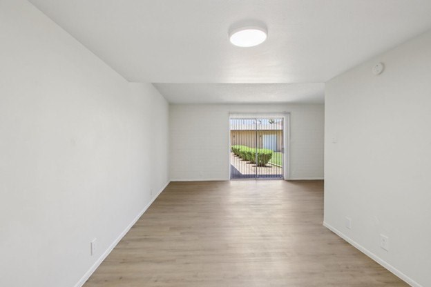 A white room with a wooden floor and a window.