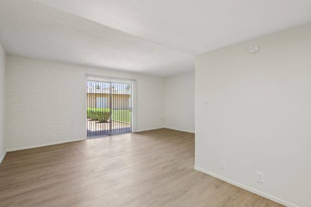 A room with a wooden floor and a window with blinds.