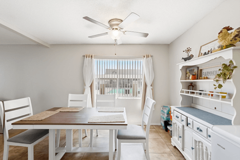 A white dining room with a wooden table and chairs.