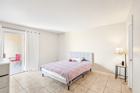 A bedroom with a bed, chair, and nightstand.