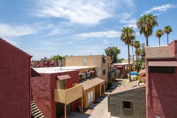A view of a courtyard with a building and palm trees.
