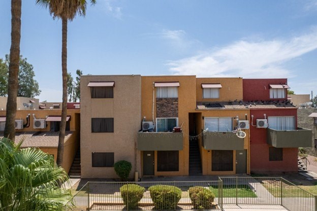 A modern two-story building with balconies and a red awning.