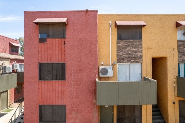 A red building with a balcony and an air conditioning unit.