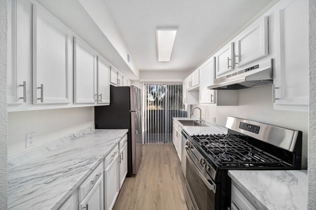 A modern kitchen with white cabinets and a black stove top oven.