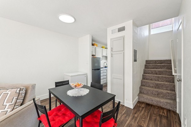 A black dining table with red chairs is in a white room.