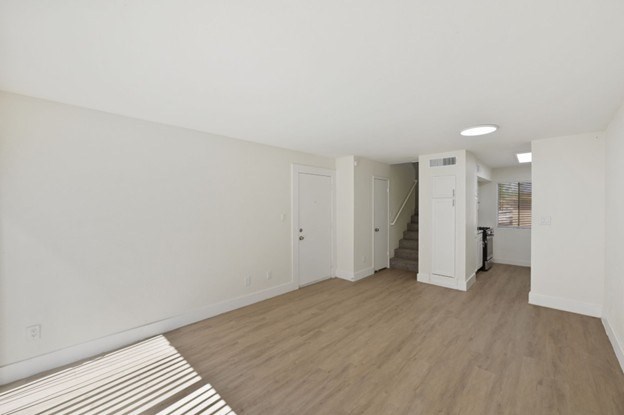 A room with white walls and wooden flooring with a striped rug.