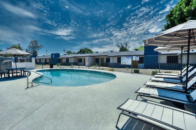A swimming pool surrounded by sun loungers and umbrellas. at Connect on University, Mesa, 85203