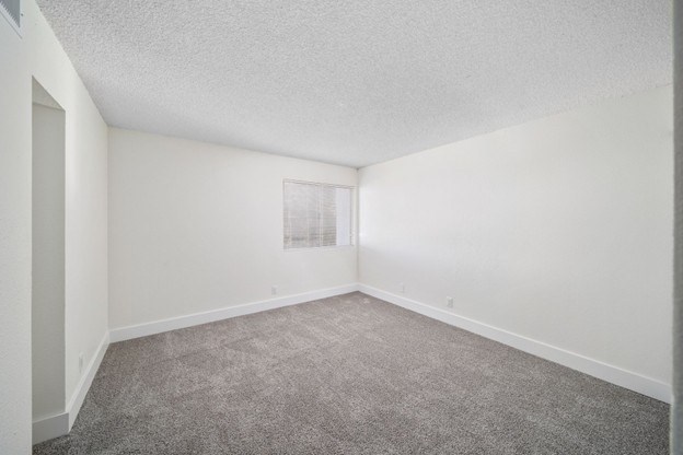 A room with a carpeted floor and a picture frame on the wall.