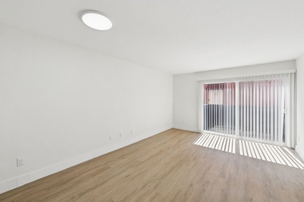 A room with a window and a wooden floor.