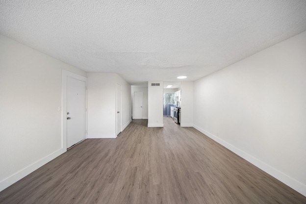 A long hallway with wood floors and white walls.