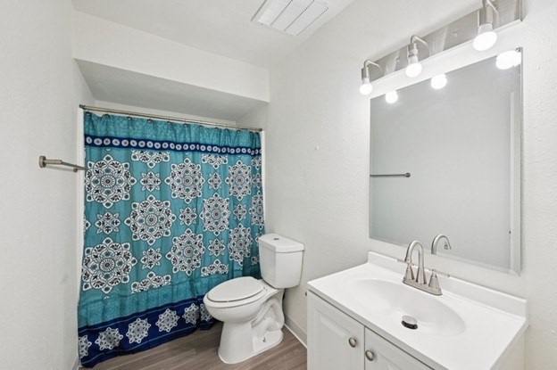 A white toilet sits next to a sink in a bathroom with a blue shower curtain.