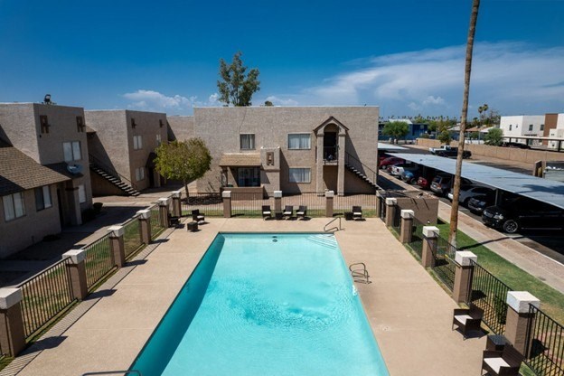 A swimming pool in front of a building with a fence around it.