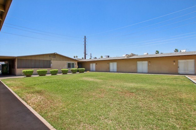 A large grassy area in front of a building with a clear blue sky above.