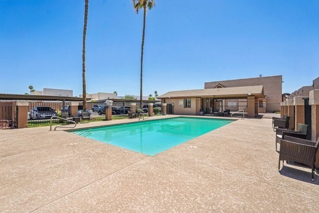 A pool surrounded by a patio and chairs.