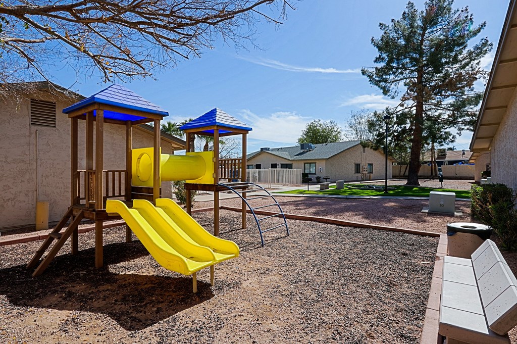 A playground with a yellow slide and a blue roofed structure.