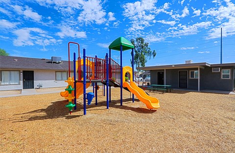 A playground with a yellow slide and a green canopy.
