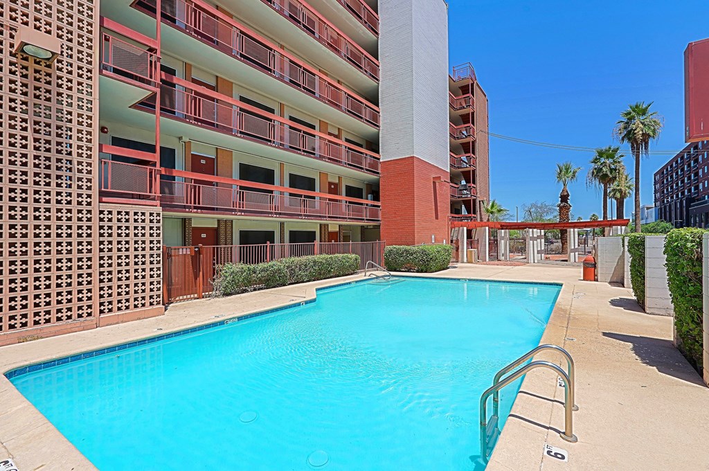 A large swimming pool is surrounded by a red brick building.