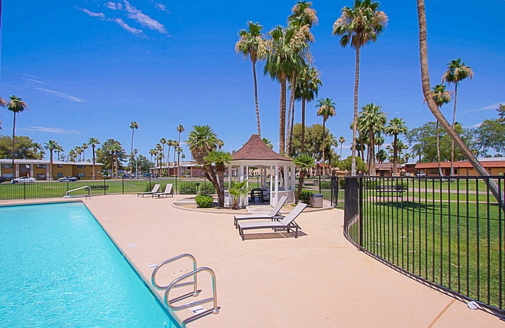 a pool with a gazebo and palm trees in the background