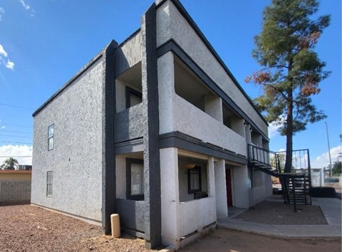 A grey building with a tree in front.