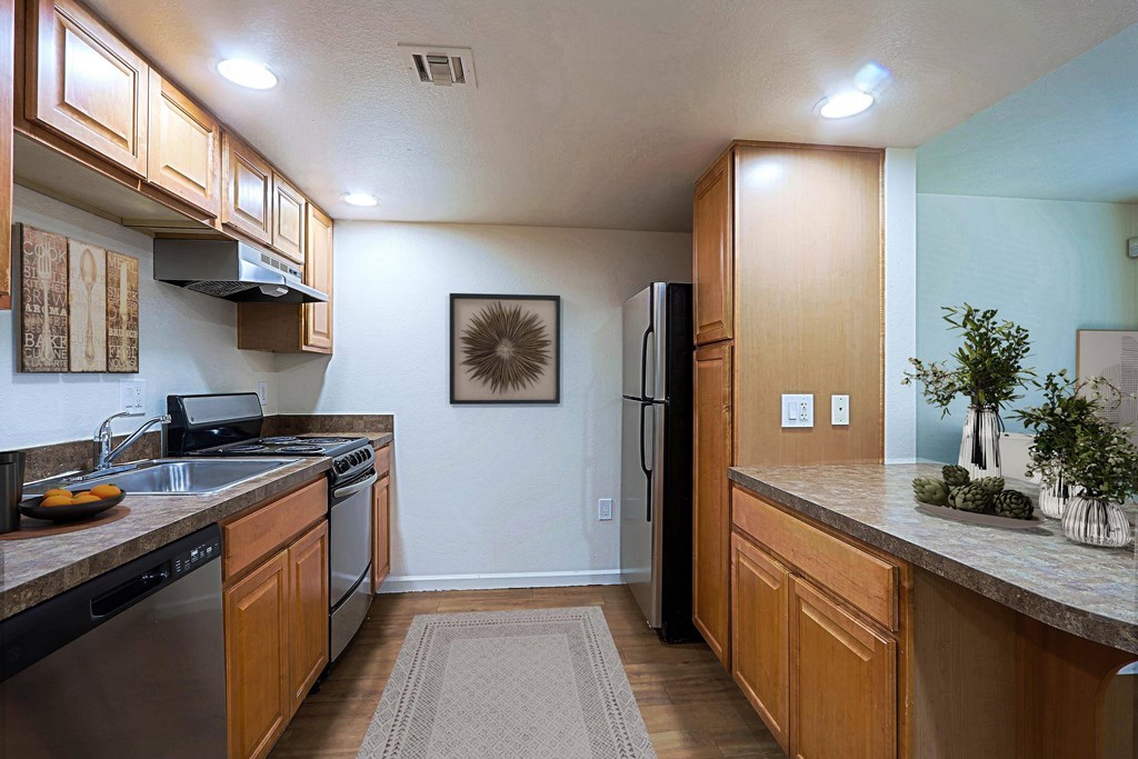 A kitchen with wooden cabinets and a black refrigerator.