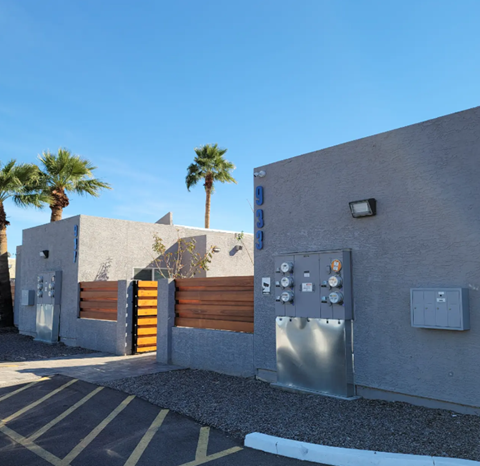 a gray building with a gate and palm trees