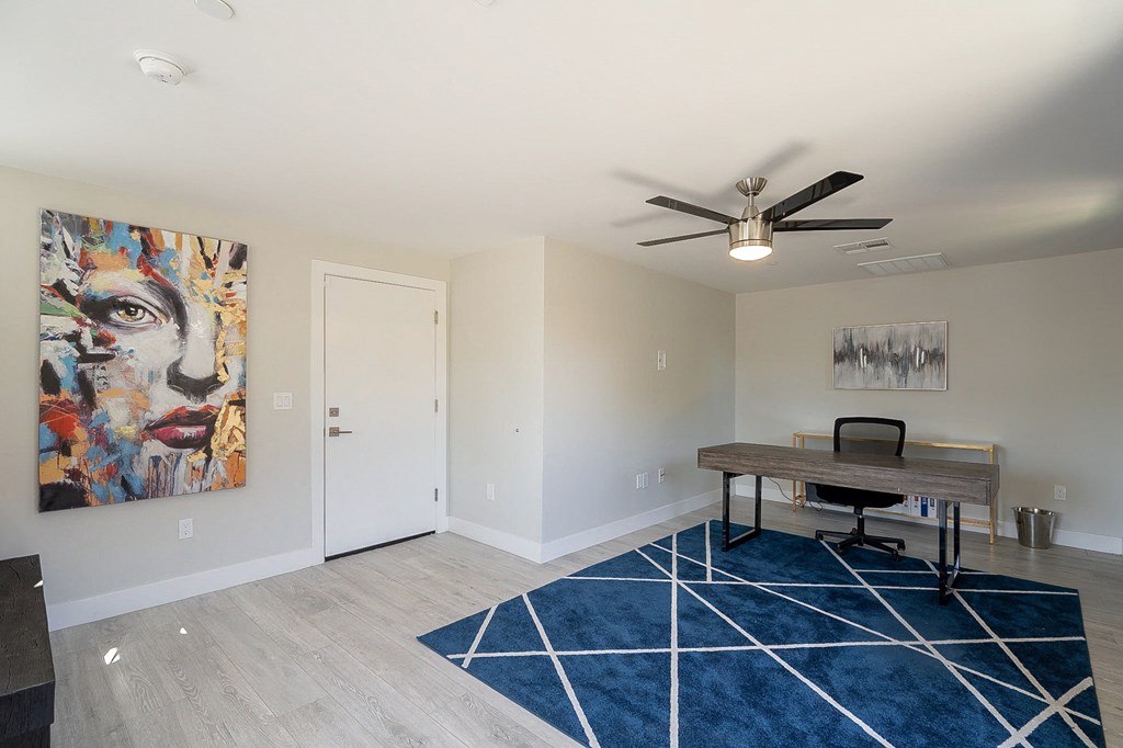 a home office with a desk and a ceiling fan