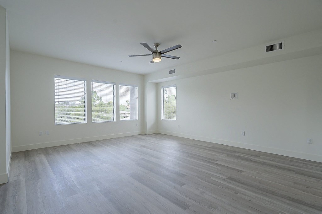 an empty living room with white walls and a ceiling fan