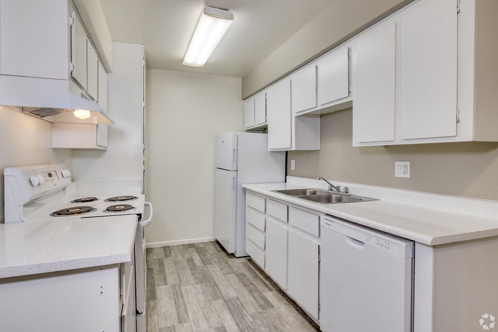 an empty kitchen with white cabinets and a sink and refrigerator