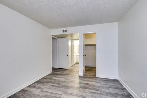 the living room of an apartment with white walls and wood flooring