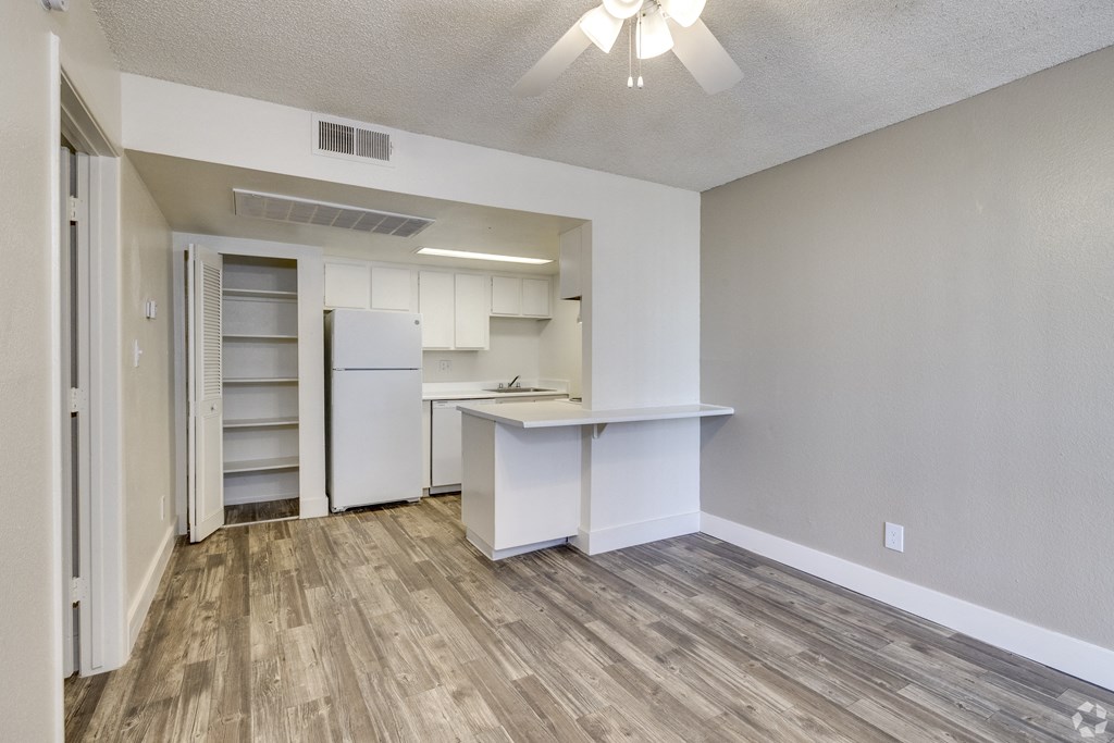 an empty living room and kitchen with a white refrigerator and